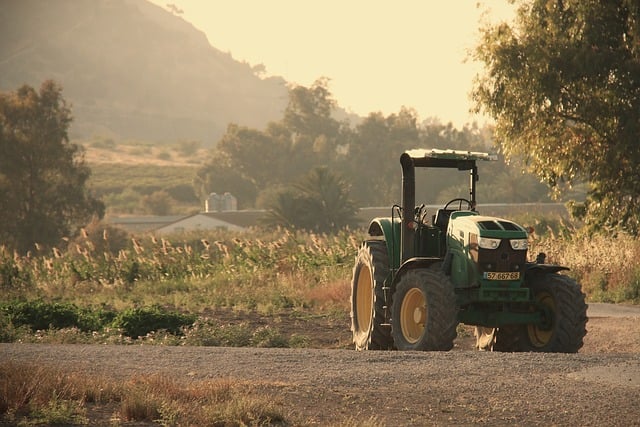 Tractor agrícola sobre un camino rural de grava en entorno natural, ejemplo de construcción rural sostenible