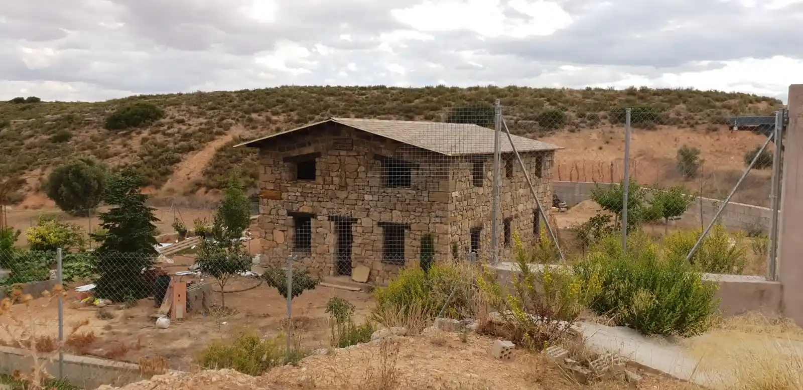 Construcción rural tradicional con panel sándwich teja envejecida integrada en una vivienda rural híbrida